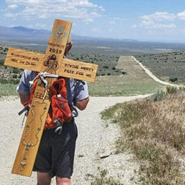 On his back he carries one of two handmade wooden crosses he made for the journey.