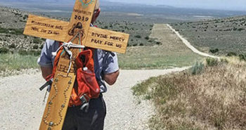 On his back he carries one of two handmade wooden crosses he made for the journey.